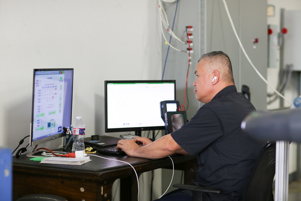 MFT technician performing precision flow meter calibration in laboratory